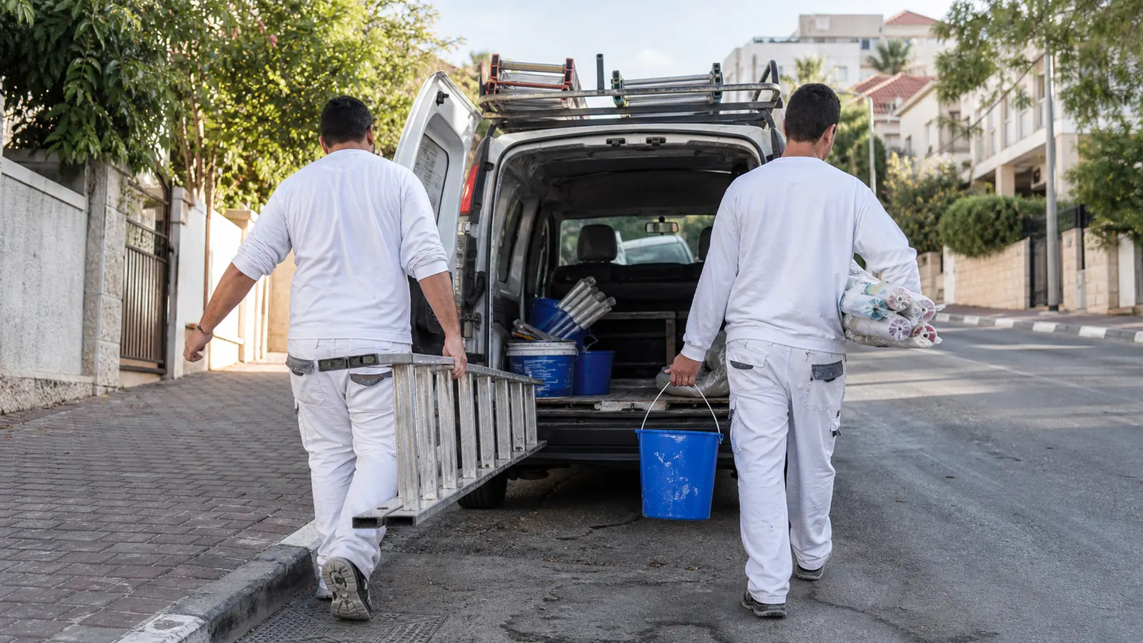 שני צבעים פורקים ציוד מרכב עבודה בתחילת יום — סולמות, גלילים ודליים כחולים